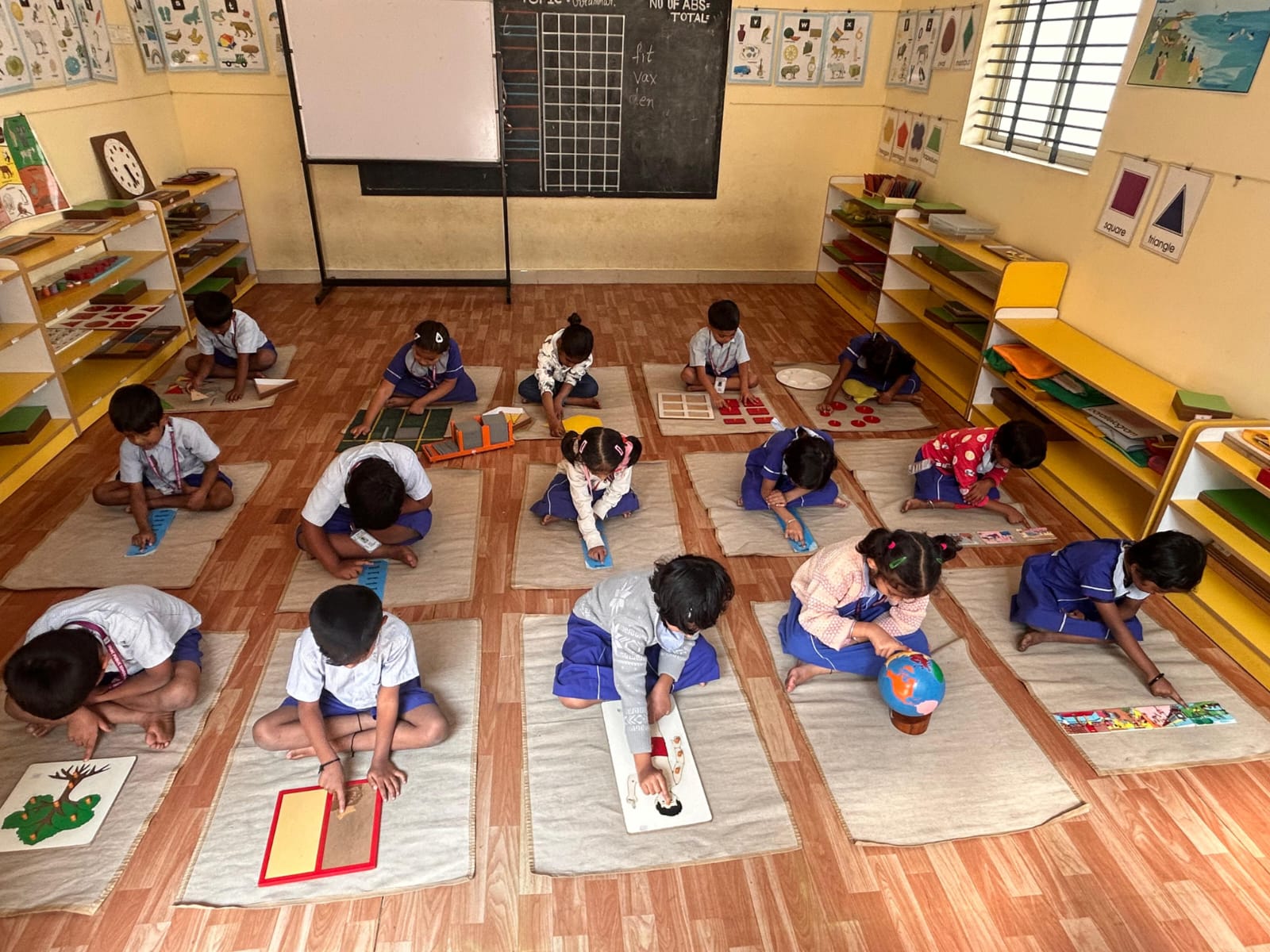 Young children working independently with Montessori materials on individual mats